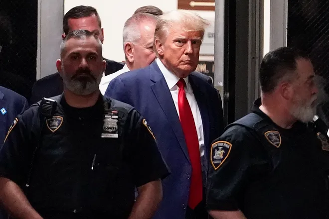 Trump looks at a news camera as he is escorted by NYPD officers into the Manhattan Courthouse on April 4, 2023.  (USA Today)
