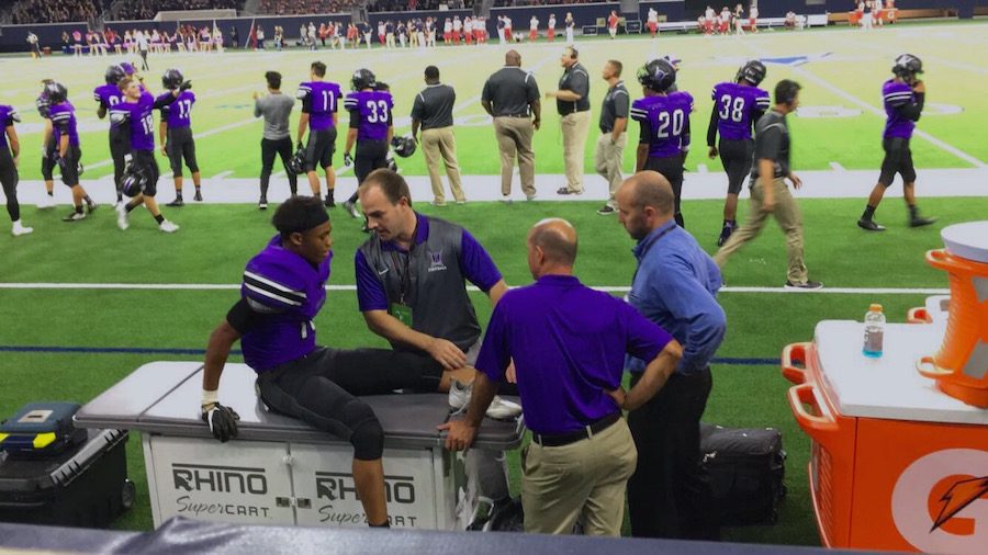 Varsity football player Kobe Bivins gets evaluated by trainers at the football game against Centennial High School.
