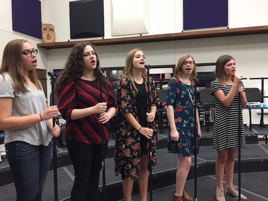 Christine Crane, Paige Romero, Elyssa Davis, Morgan Wooley, and Sydney Copeland are practicing songs for their upcoming performance. 
