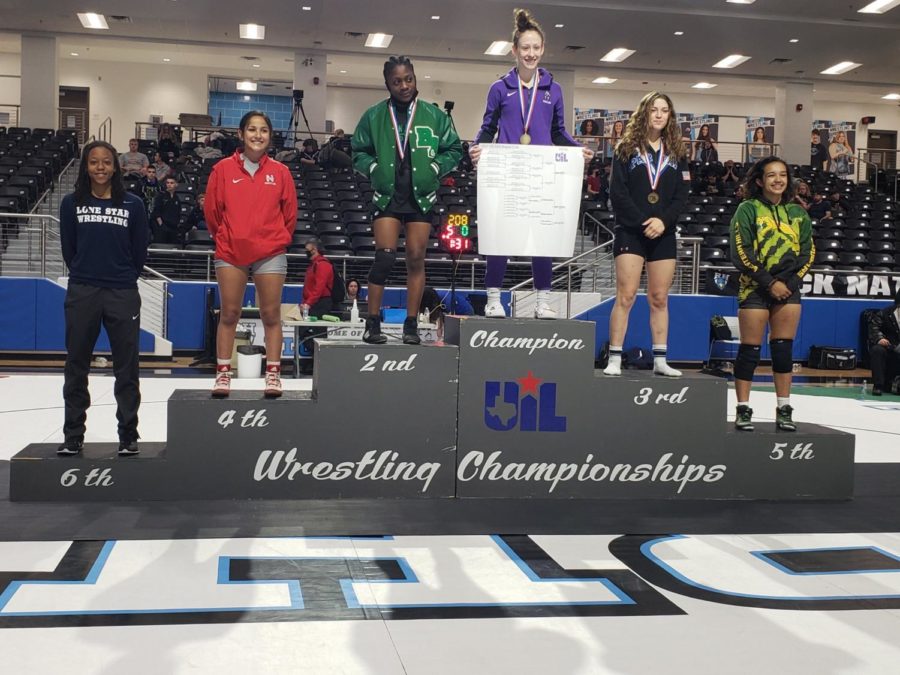 Tabitha Wood stands on top of the podium after finishing first in her weight class at regionals. This win qualified her for the state wrestling meet. (Knight Press/IHS Knight Press Twitter)