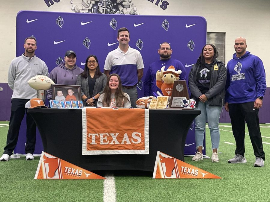 Brighton Mooney officially signs her letter of intent to run track at UT Austin surrounded by her coaches and other staff members.

