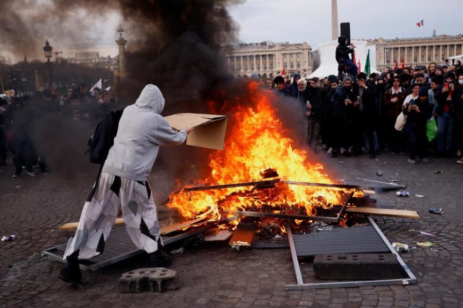 A protester throws cardboard to keep the fire going on March 16, 2023, at Concorde square near the National Assembly. (AP/Thomas Padilla)